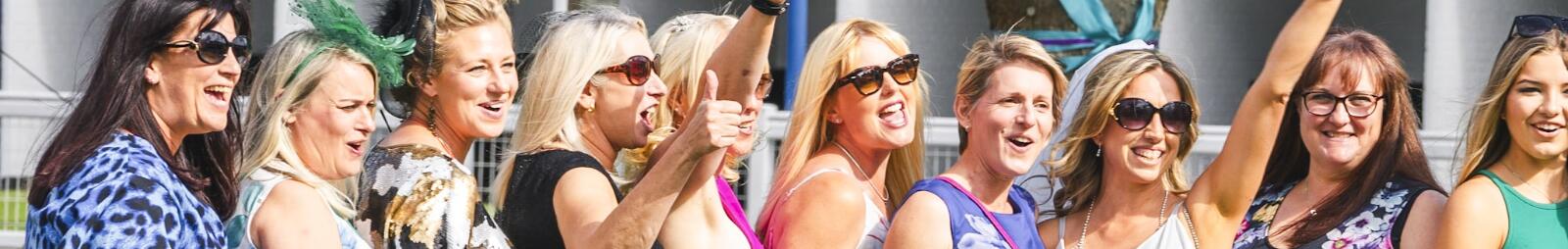 A large hen party poses in a line with the bride to be at Windsor Races.