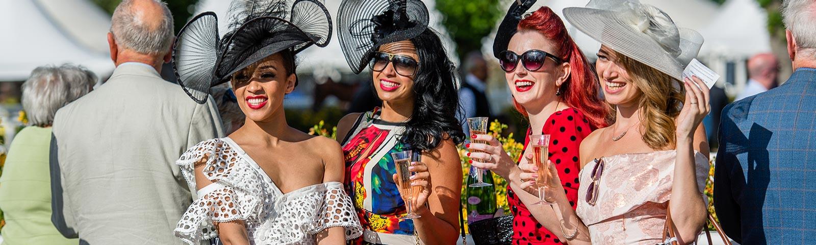 Four well dressed ladies drinking Champagne at Royal Windsor Racecourse ladies day