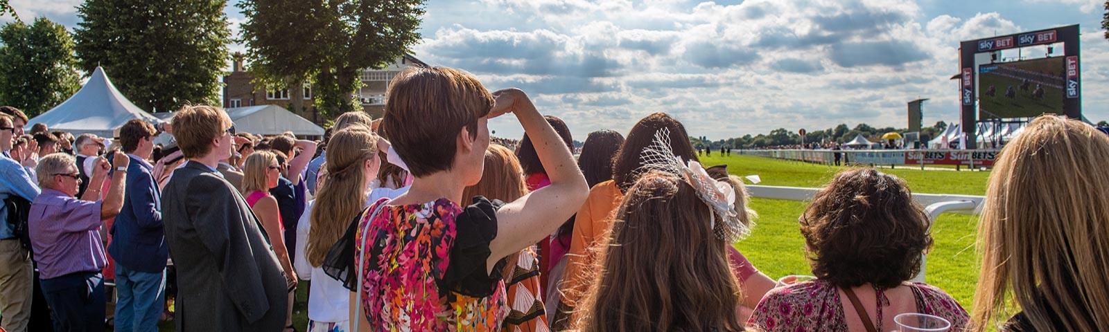 Group of racegoers watching racing from the sidelines at Windsor Racecourse.