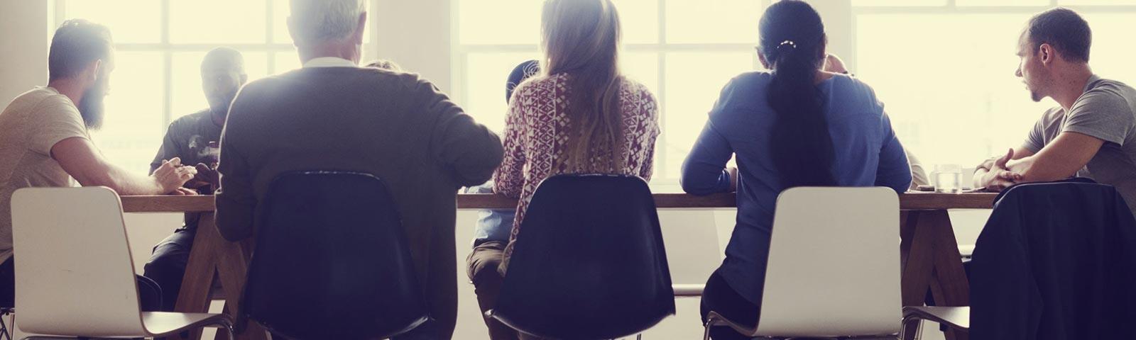 Colleagues gather around a boardroom style table.