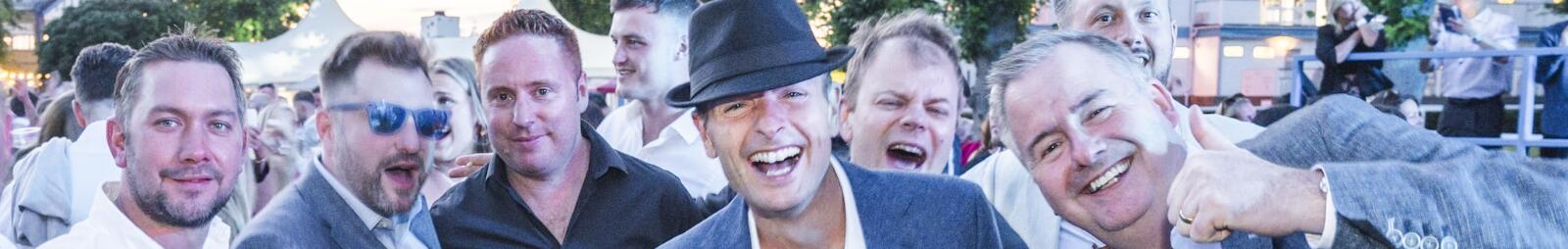 A group of race goers in suit jackets enjoying the music at Windsor Races